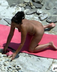 Нудистка загорает на берегу моря